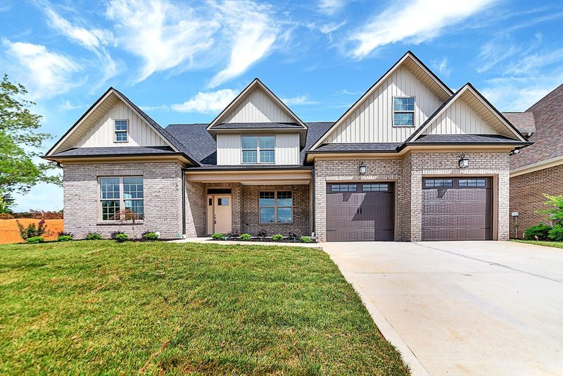 Front exterior of a brick custom home with board-and-batten gables and a two-car garage