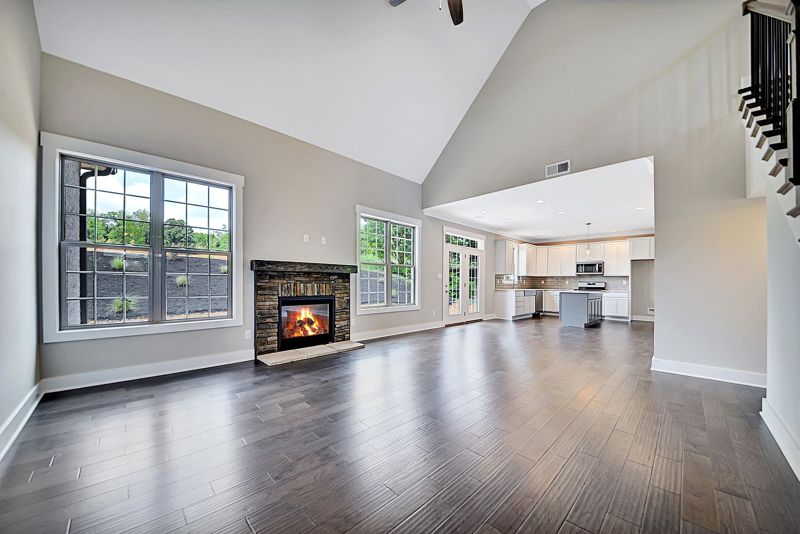 Great room with a fireplace, wood-look floors and windows to the backyard
