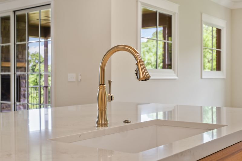 Kitchen sink with brass faucet and window view