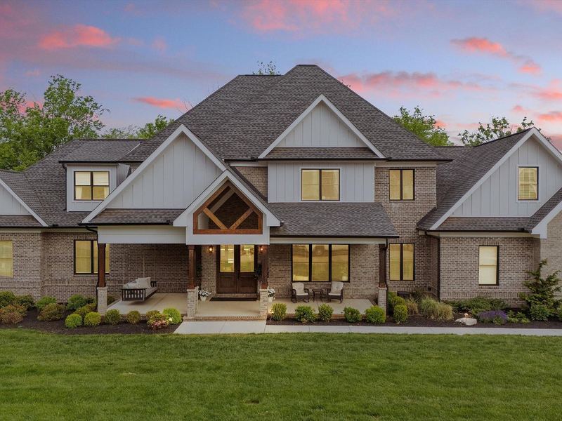 Craftsman-style home at dusk: brick, stone and timber-framed gable