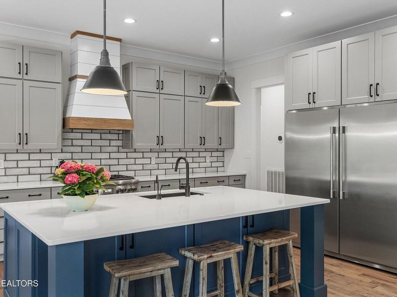 Kitchen with white cabinetry and navy island