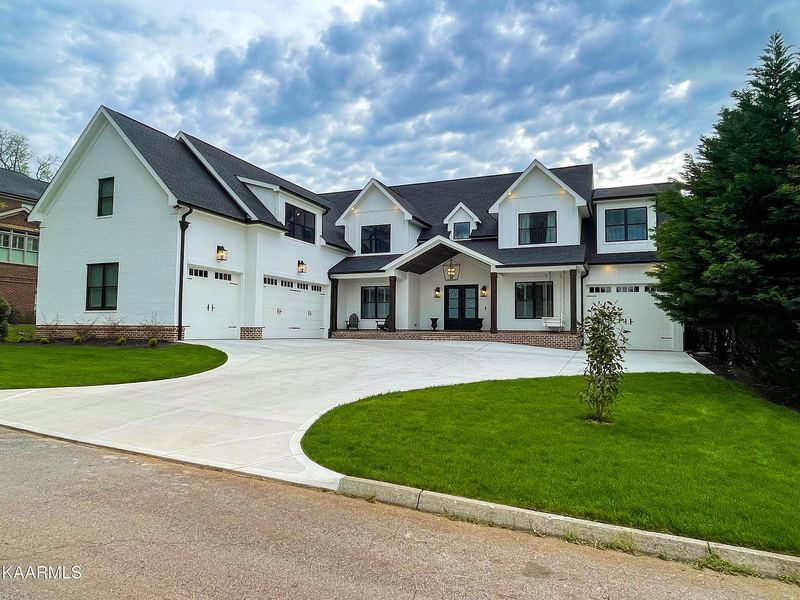 White modern farmhouse with black windows and board-and-batten gables