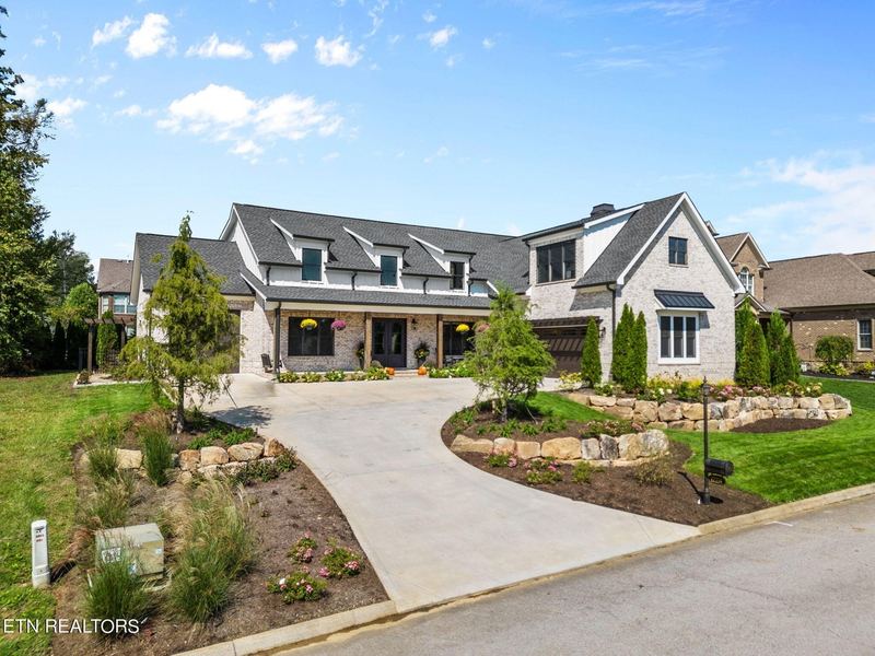 Transitional farmhouse exterior with curved driveway and stone landscaping
